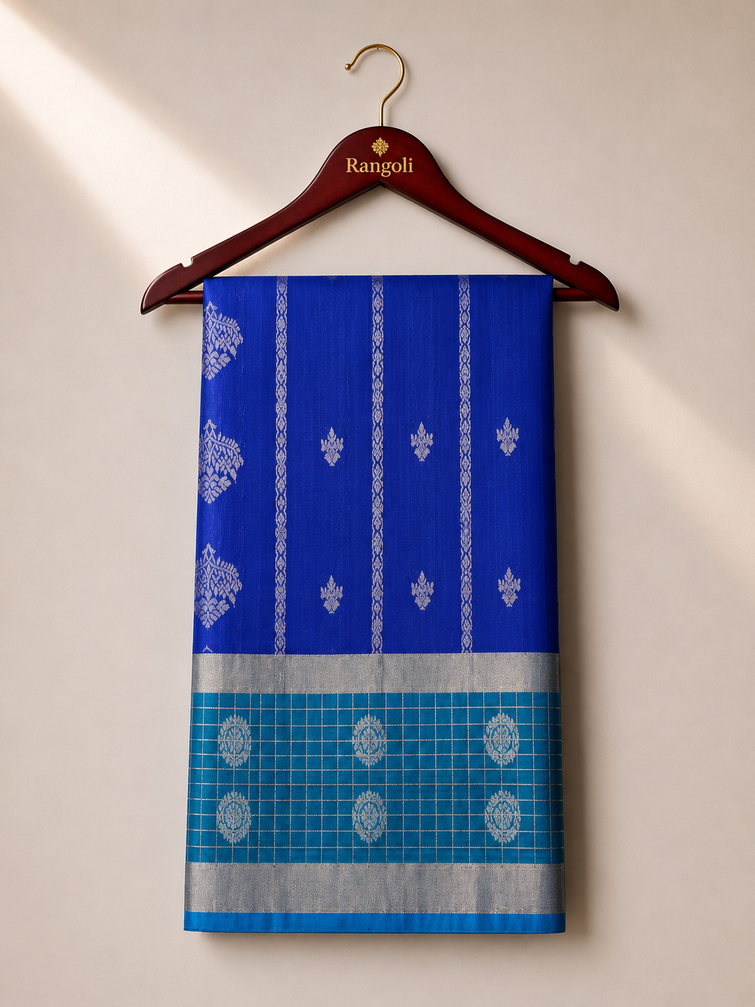 Elevate your ethnic style with this elegant royal blue silk saree, featuring intricate silver zari motifs and a striking teal checked contrast border.
