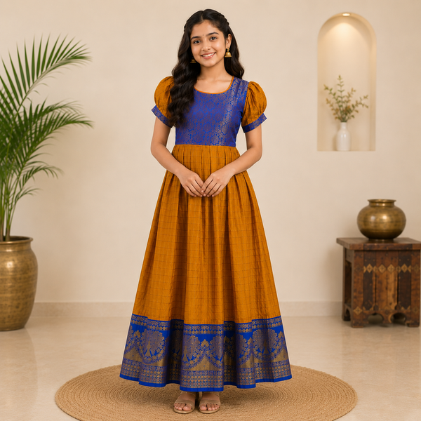 Elegant mustard and royal blue ethnic kids gown featuring a woven brocade bodice, puff sleeves, and a beautifully detailed traditional zari border for a graceful festive look.