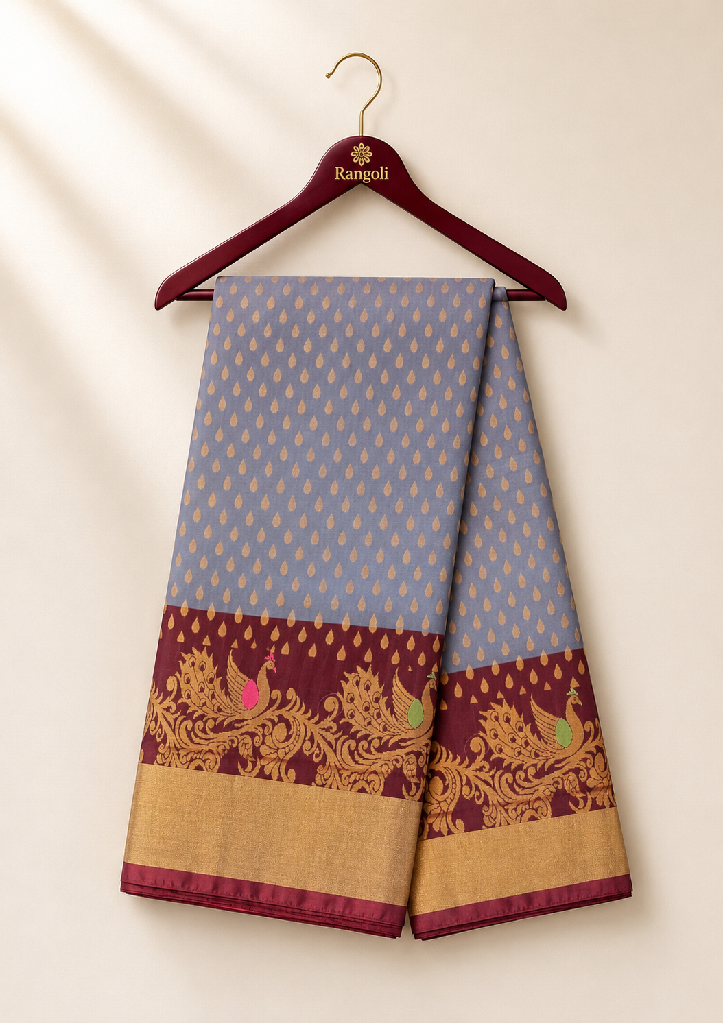 Elegant grey silk saree adorned with delicate gold buttas and a rich maroon peacock zari border for a timeless traditional look.