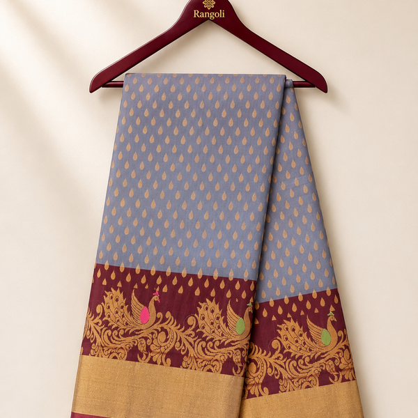 Elegant grey silk saree adorned with delicate gold buttas and a rich maroon peacock zari border for a timeless traditional look.