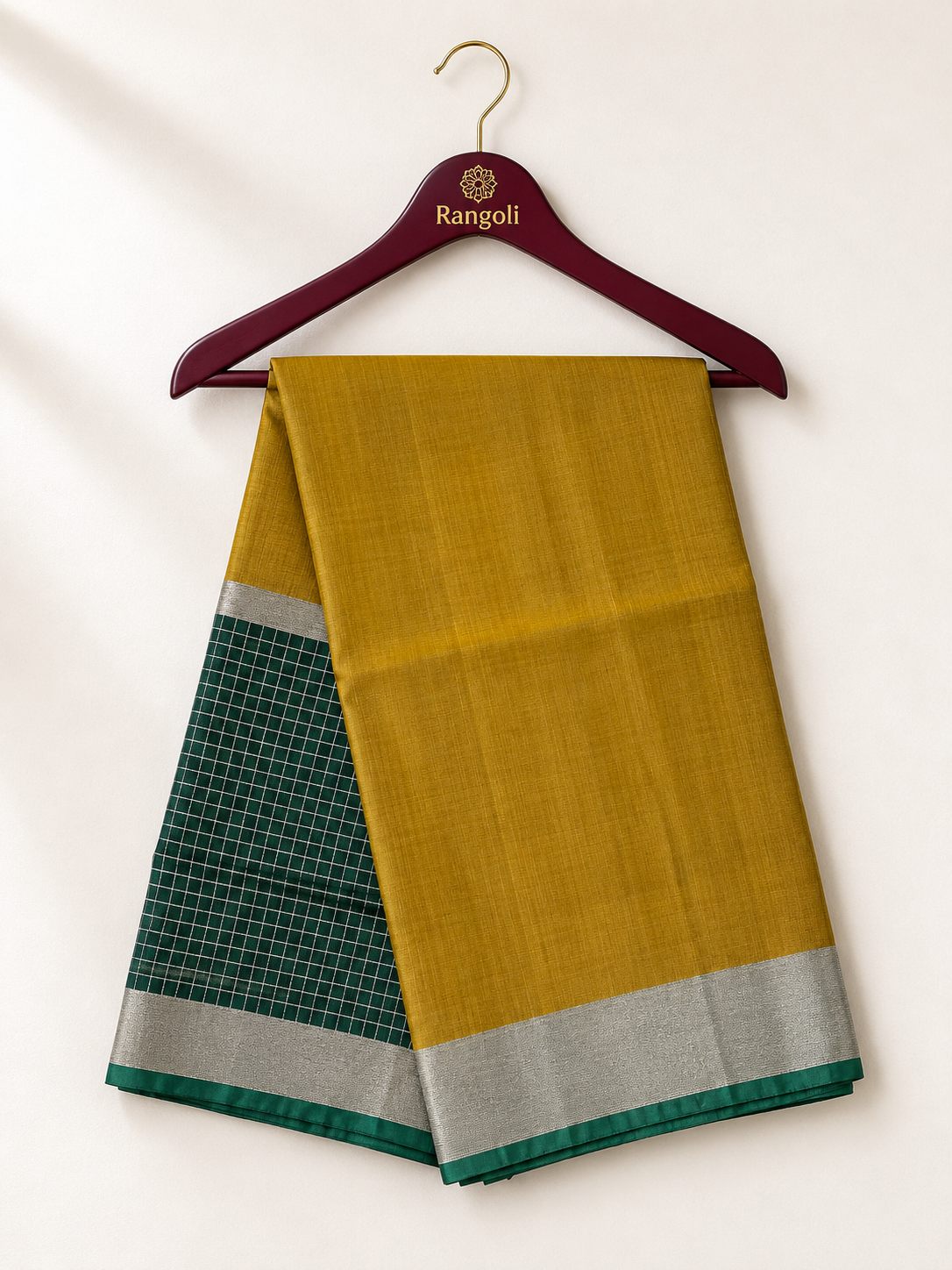 Elegant mustard gold silk saree featuring a contrasting green checked pallu with a shimmering silver zari border for a refined traditional look.