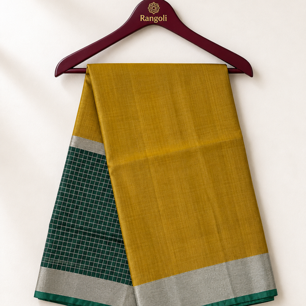 Elegant mustard gold silk saree featuring a contrasting green checked pallu with a shimmering silver zari border for a refined traditional look.