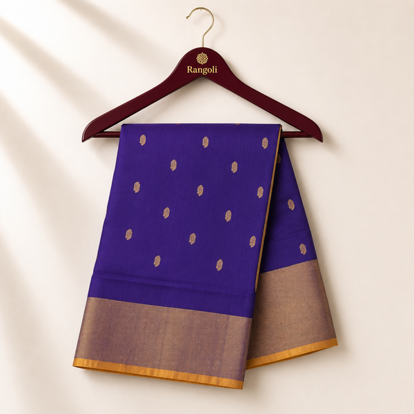 Elegant royal blue silk saree adorned with delicate gold zari buttas and a shimmering silver-gold zari border for a timeless festive look.