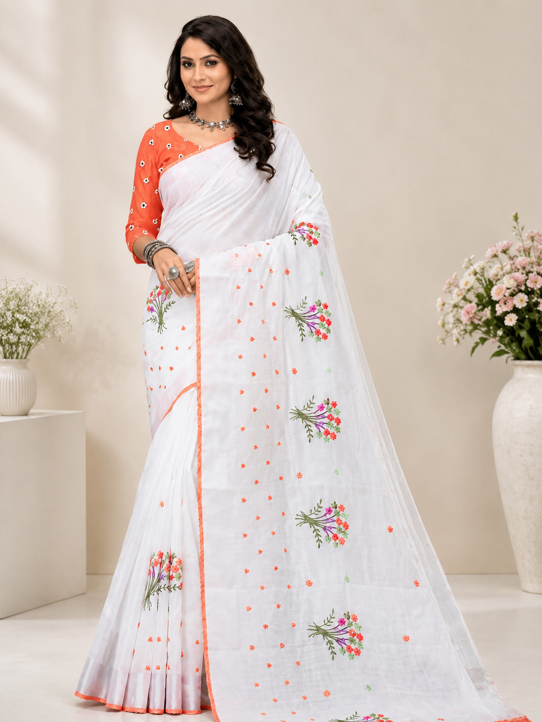 Elegant white saree adorned with delicate floral embroidery and a soft peach border for a graceful and refreshing ethnic look.