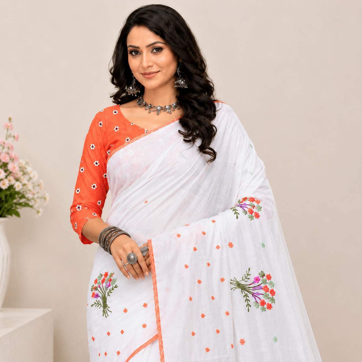 Elegant white saree adorned with delicate floral embroidery and a soft peach border for a graceful and refreshing ethnic look.