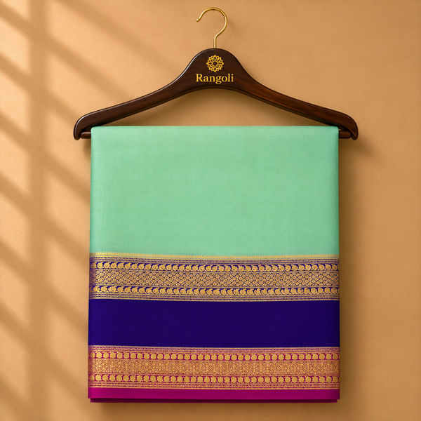 Graceful mint green Mysore silk saree featuring a rich royal blue and pink zari border with intricate traditional weaving.