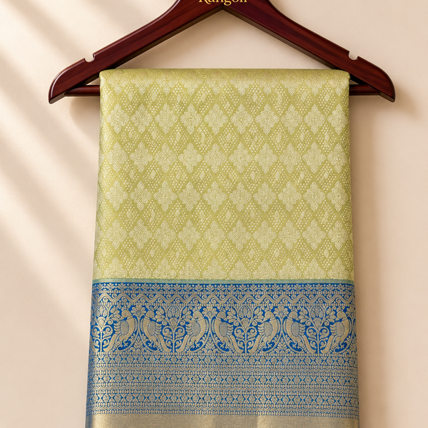 Kanchipattu lime gold saree with intricate zari weaving and a royal blue peacock motif border for a rich festive look.