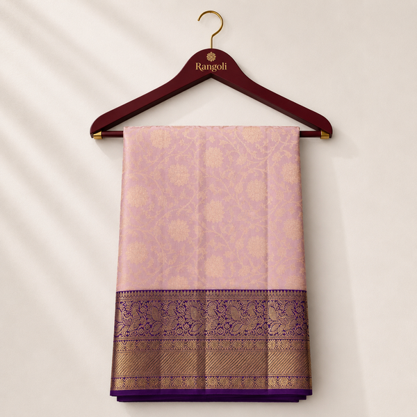 Elegant blush pink Kanchipattu silk saree featuring intricate floral zari weaving with a rich royal purple zari border for a timeless festive look.