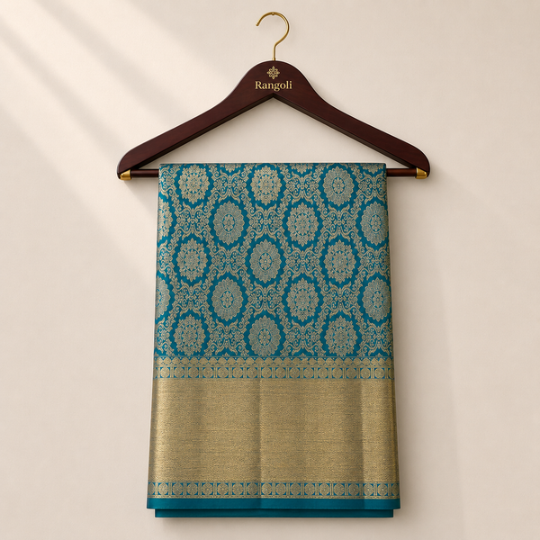 Elegant teal and antique gold Kanchipattu silk saree featuring intricate zari floral motifs with a rich golden border for a regal festive look.