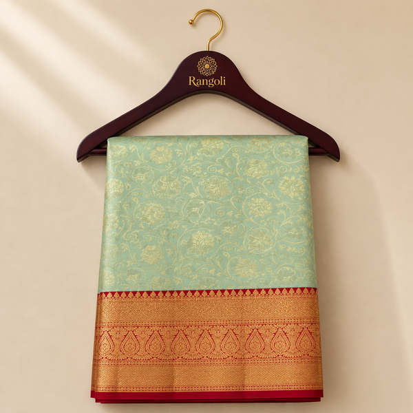 Pastel mint green Kanchipattu saree featuring elegant gold floral vine weaving with a rich red zari border.