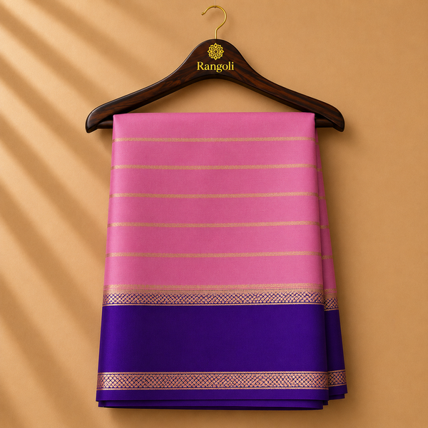 Graceful pastel pink Mysore Silk saree featuring subtle gold zari stripes and a rich royal purple border with elegant zari detailing.